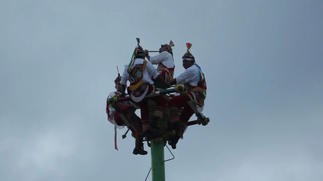 close up Papantla dancers on the top of the pole playing drums during a cloudy day