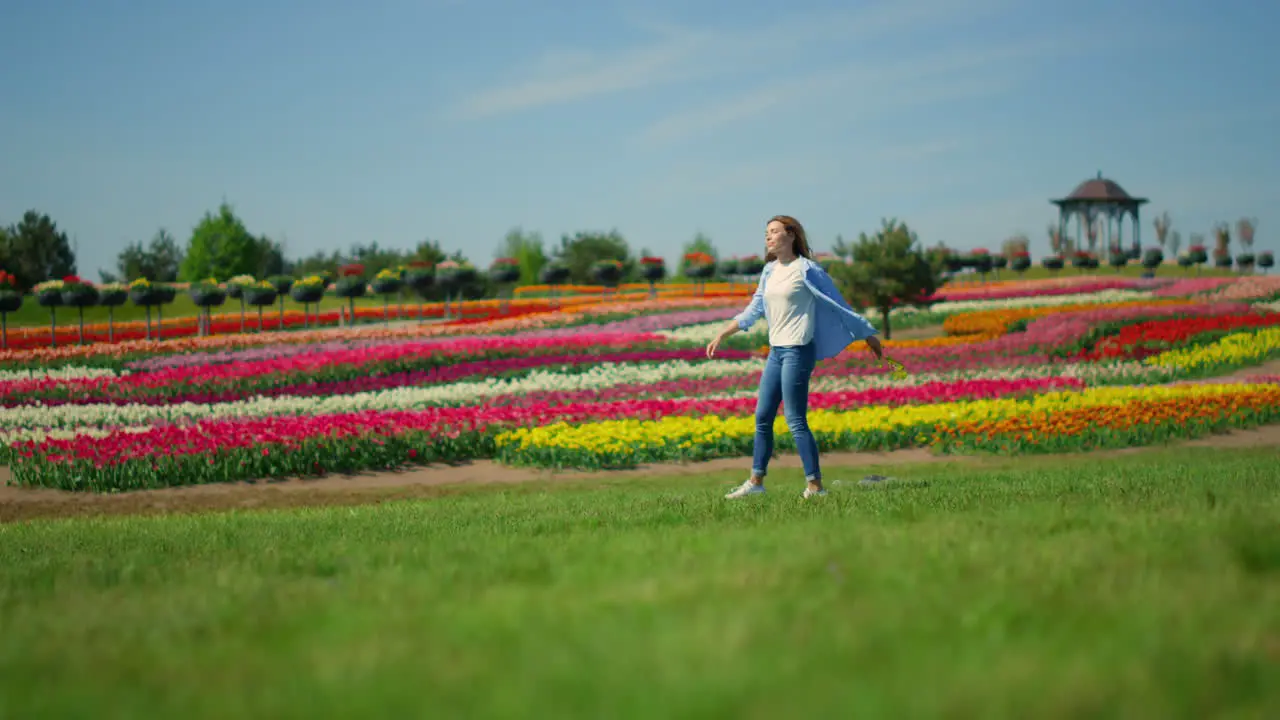 Unknown woman in casual clothes walking in beautiful spring garden in daytime