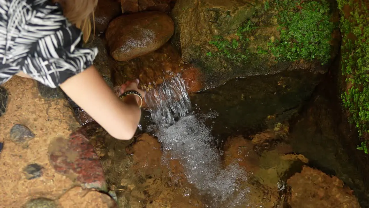 Thirsty person drinking refreshing water from spring in cave handheld