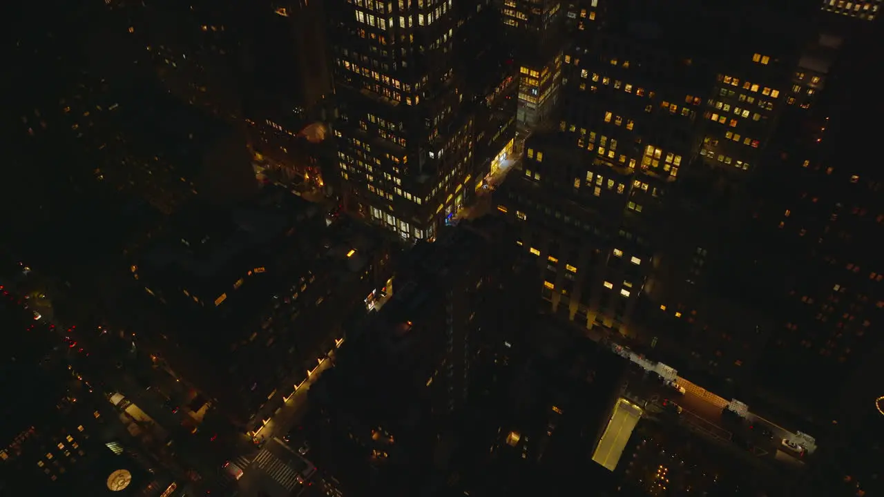 High angle view of streets in night city Tilt up reveal of high rise buildings with lighted windows in midtown Manhattan New York City USA