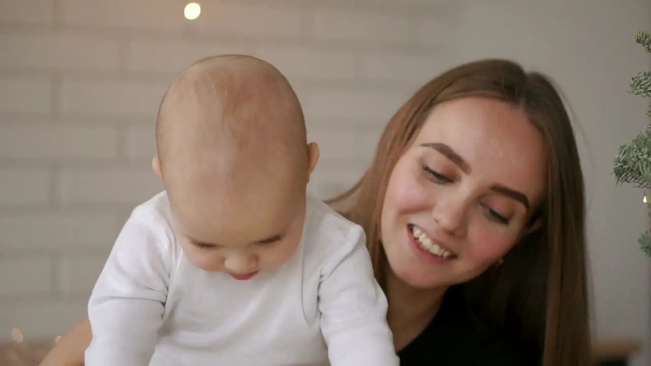 Mom and and baby sitting at the table playing tablet computer pressing your fingers on the screen and laughing