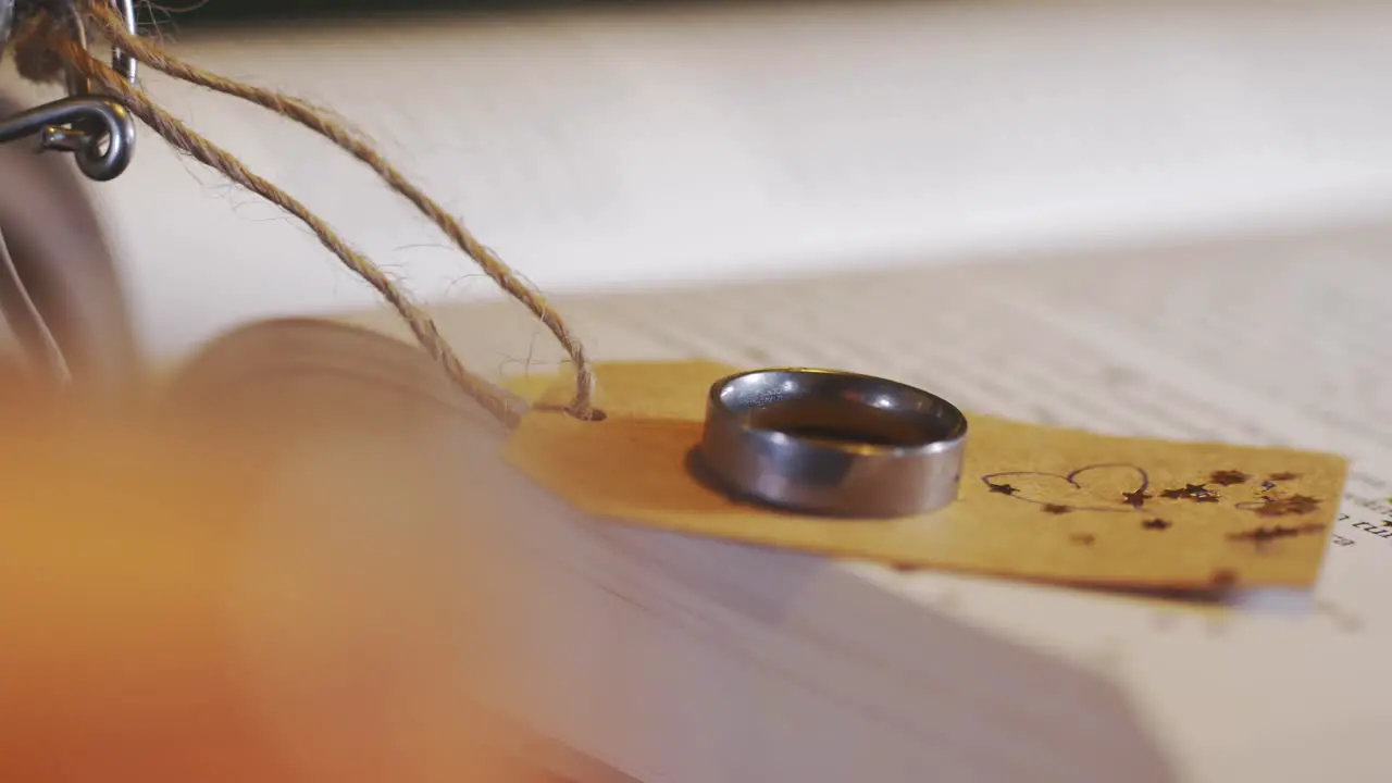 Slider reveal of ring placed on tag with a heart tied to a glass bottle