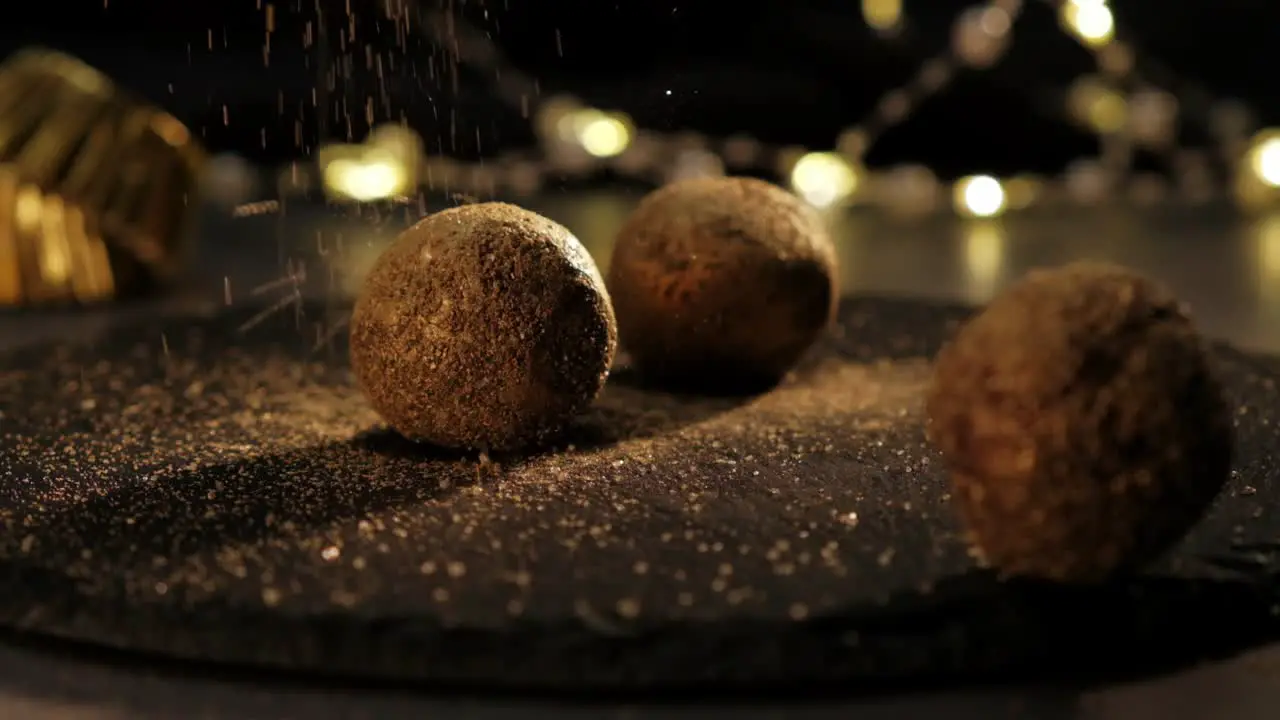 Slowmotion of golden sugar falling over chocolate truffles