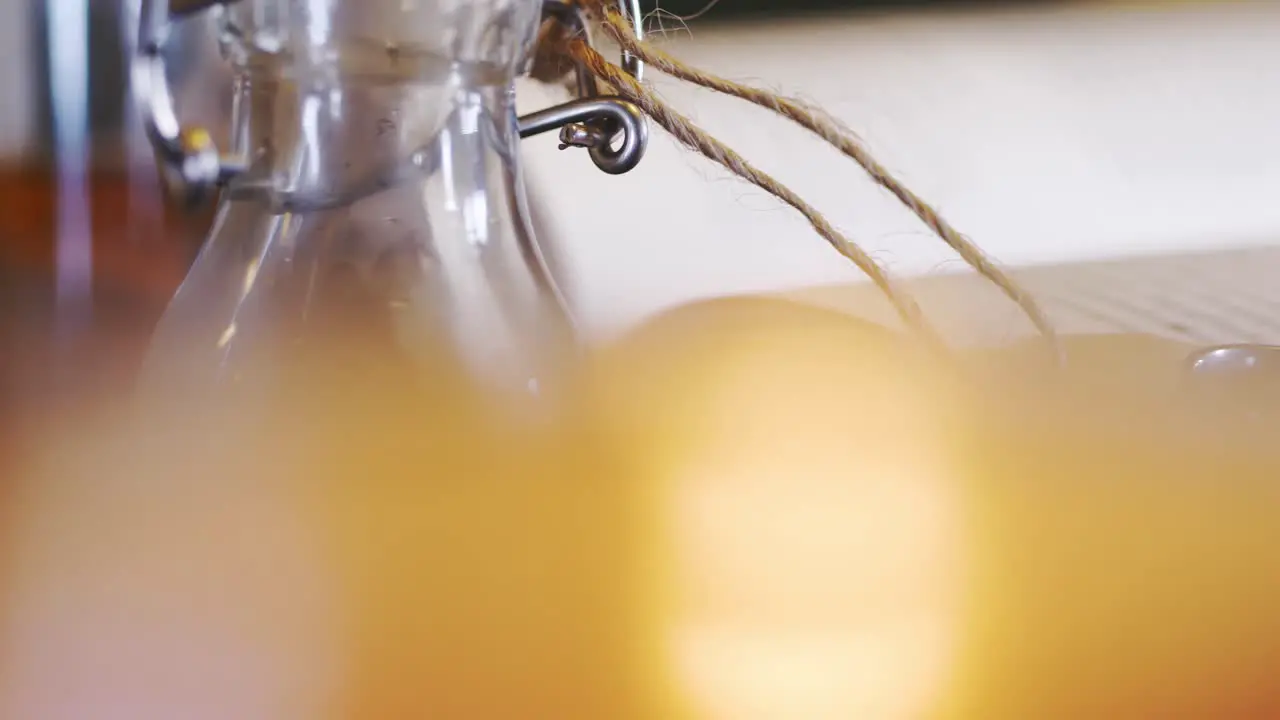 Blurry candle lit in front of glass bottle with tag and band slider close up