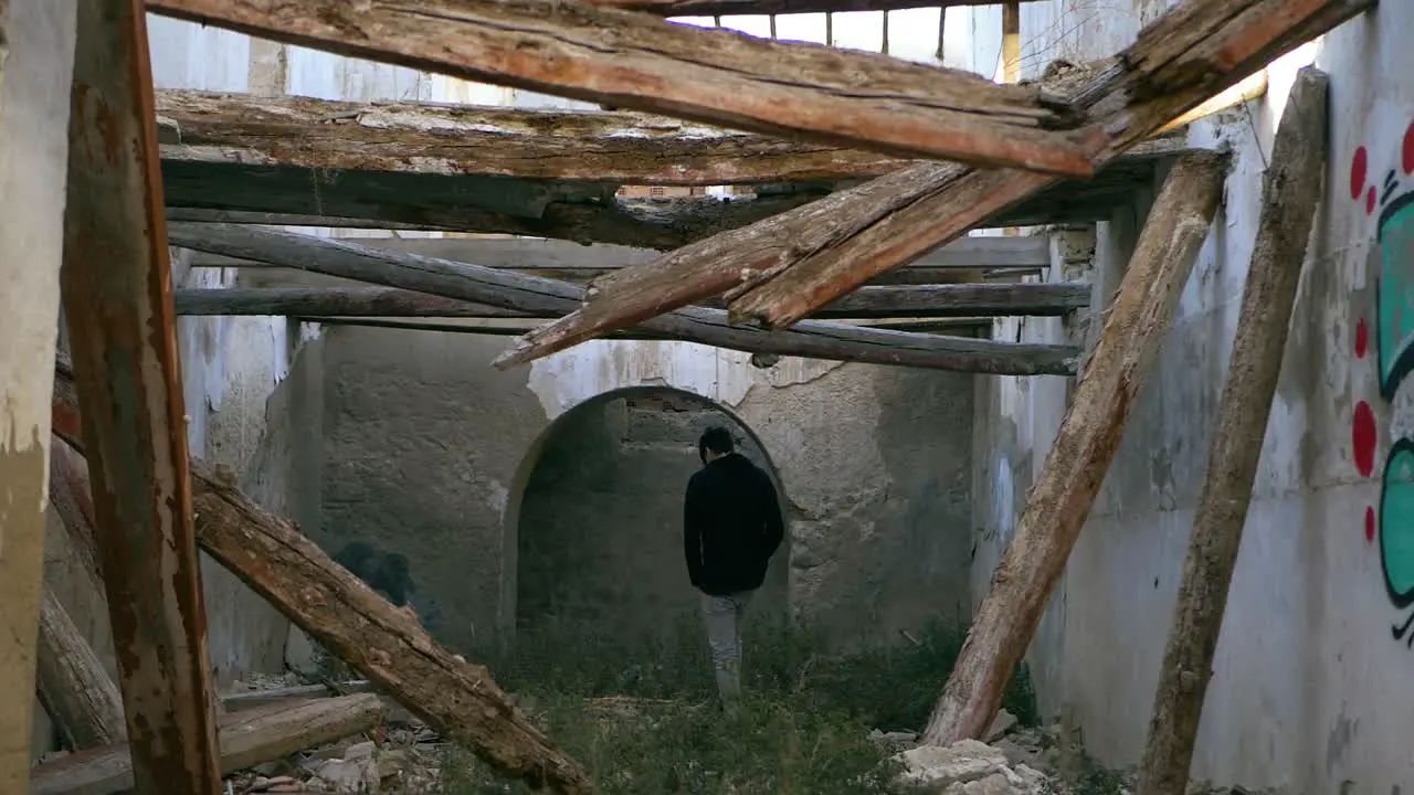 Young man teenager walks through abandoned place with collapsed beams