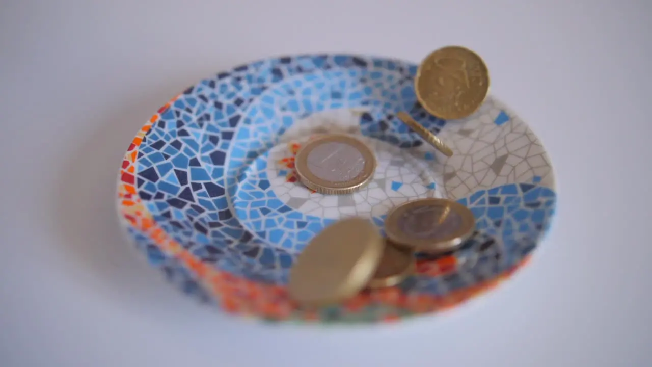 Euro coins falling in a glass vessel on a table 