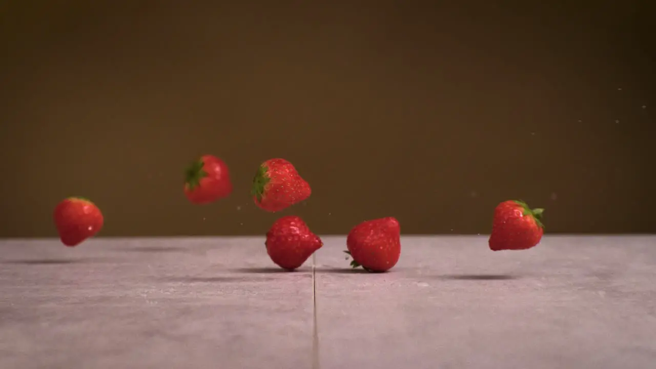 Strawberries falling on surface and water splashes everywhere in super slow motion 1000fps 4k Impact