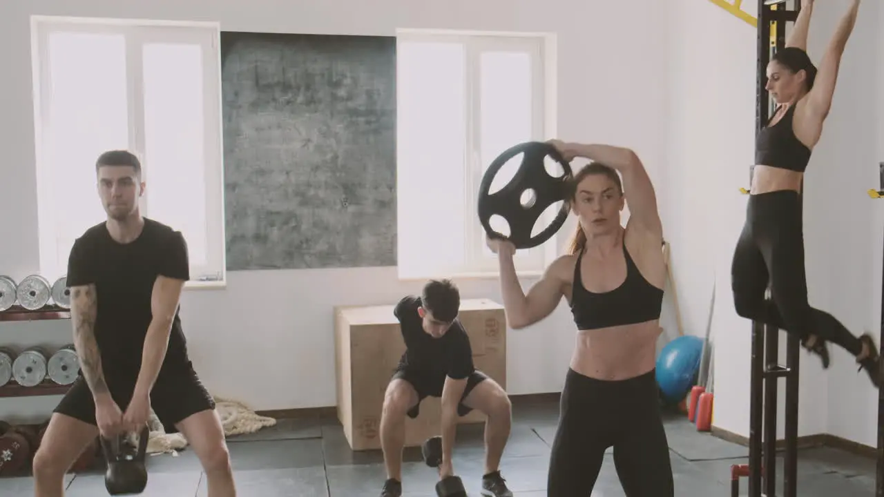 A Crossfit Group Made Up Of Women And Men Work On Different Exercises