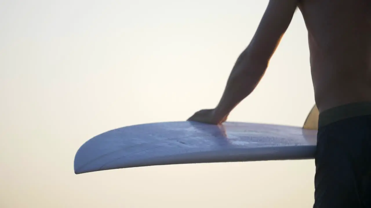 Man Carrying and Wiping Off a Surfboard