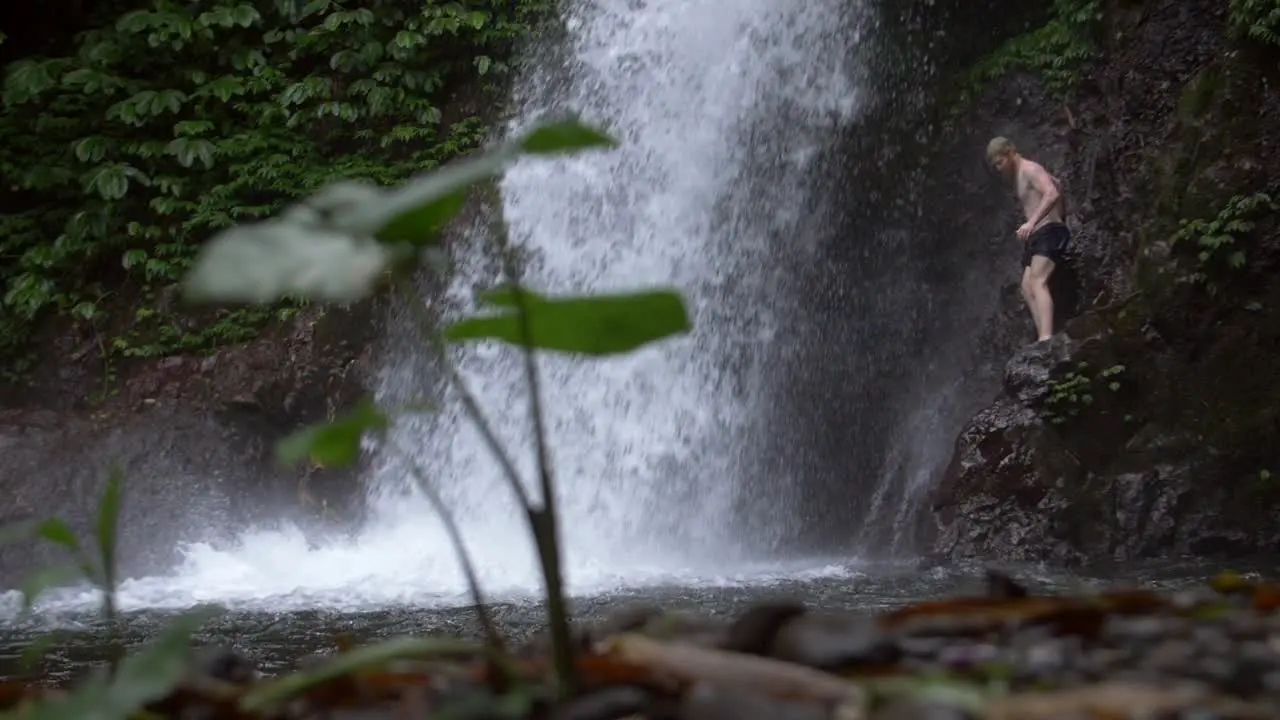 Man on a Ledge by a Waterfall