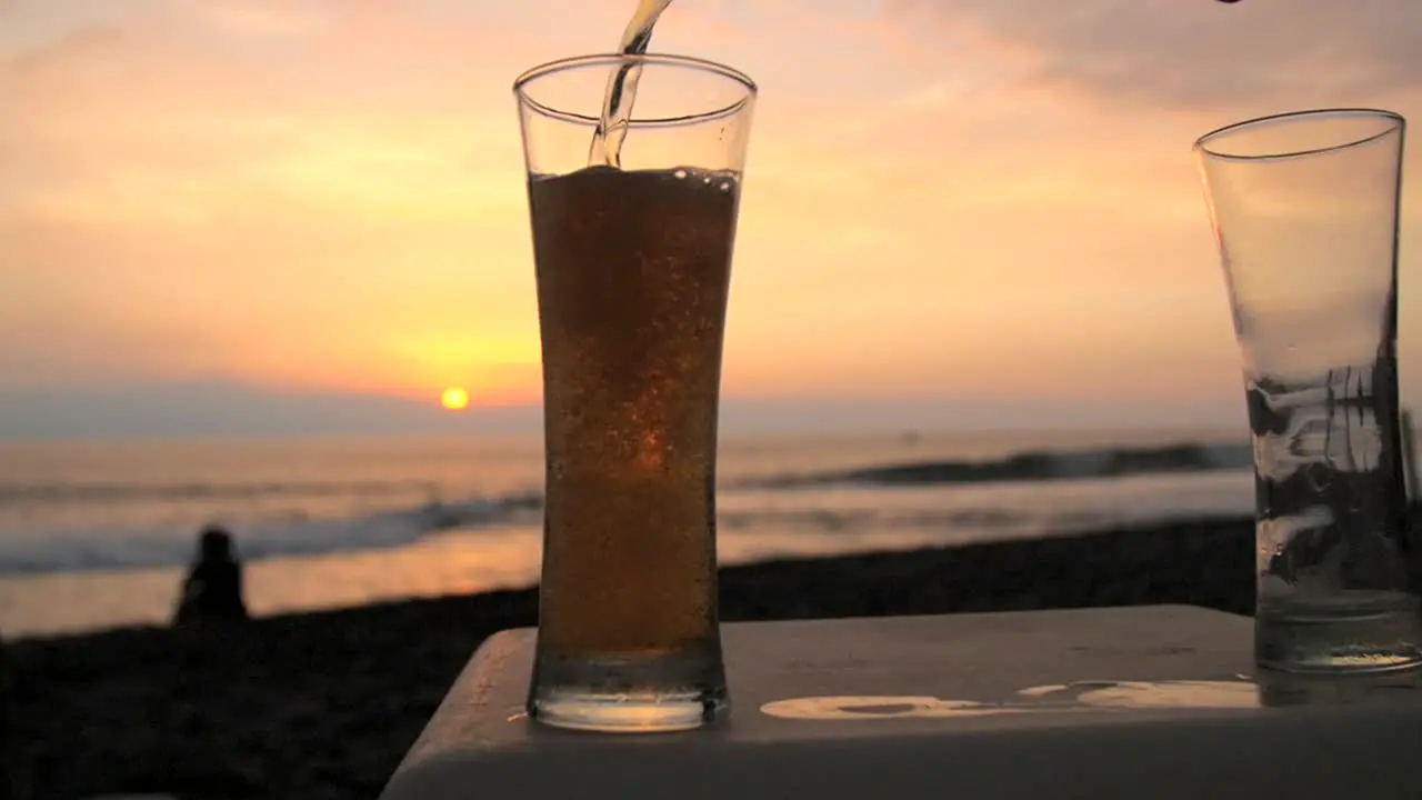 Pouring Beer in a Glass on a Beach at Sunset