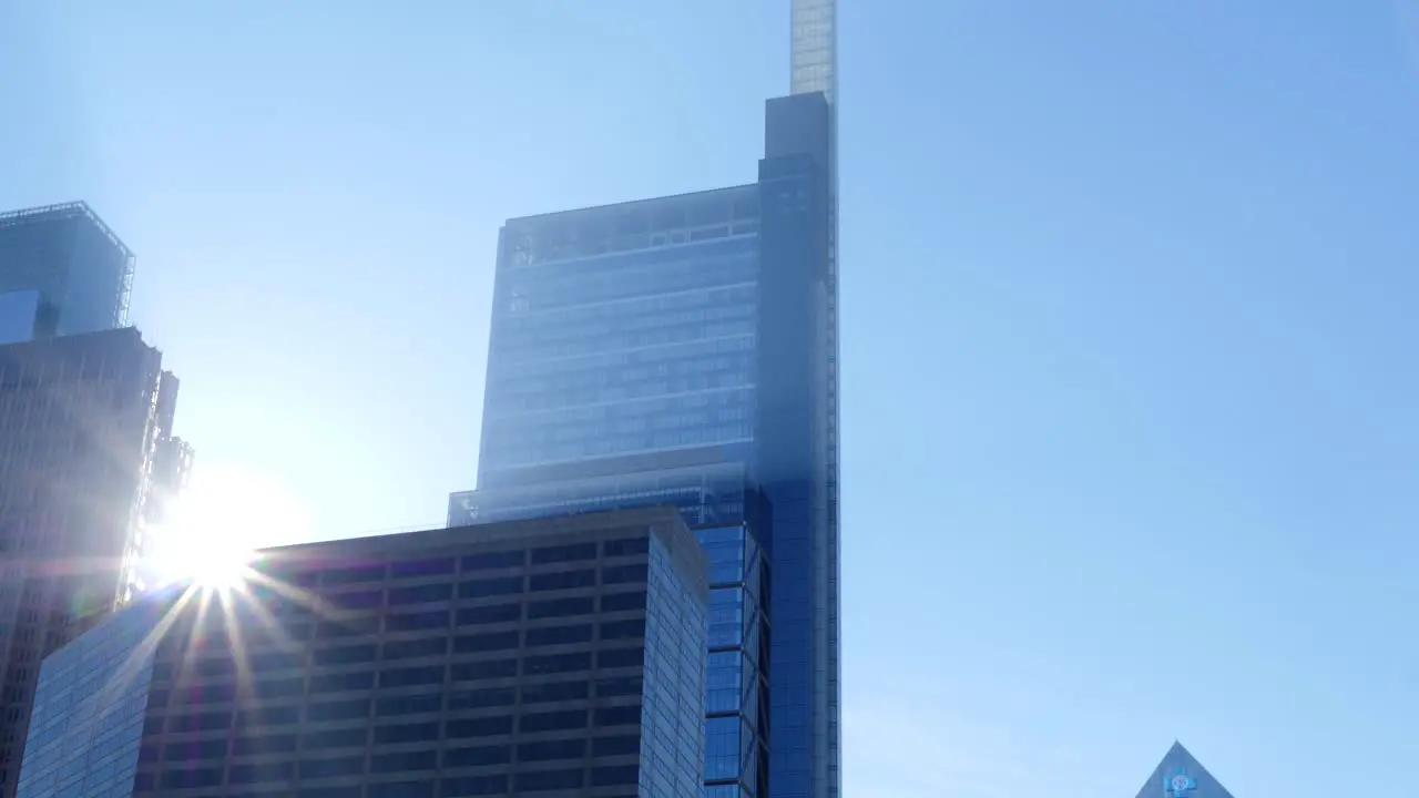 Sun peaks through corporate skyscrapers in slow motion