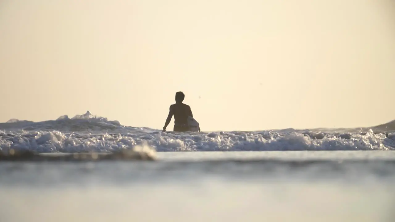 Low Shot of a Surfer Walking in the Sea