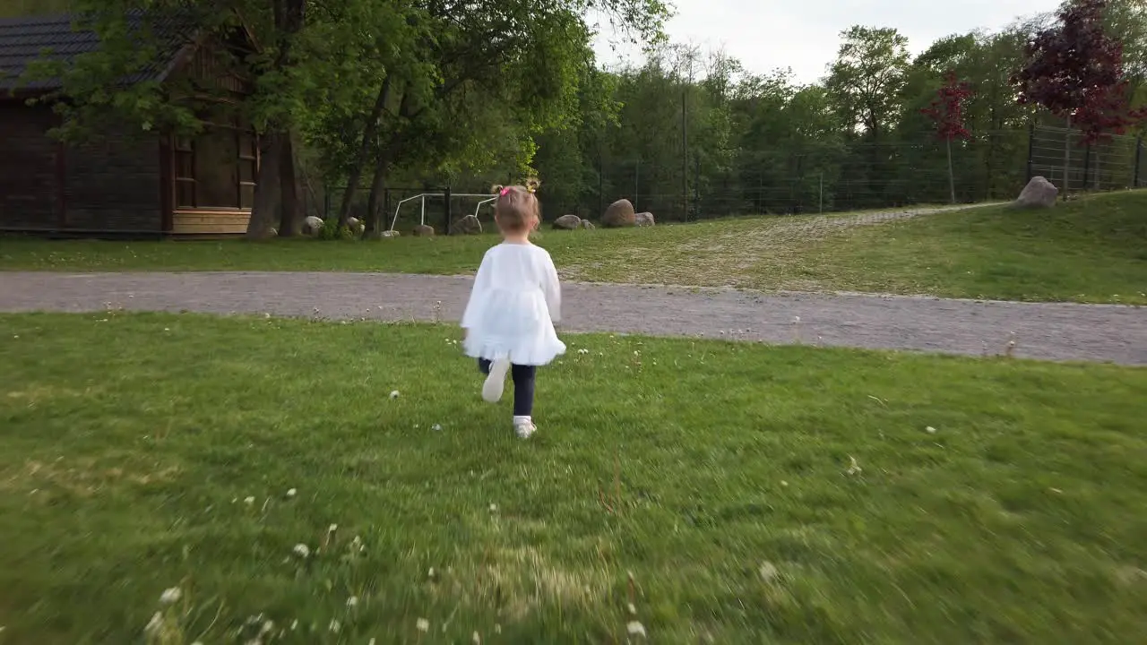 Little Toddler Girl Runs on the Grass Camera from Behind 4K Slow Motion