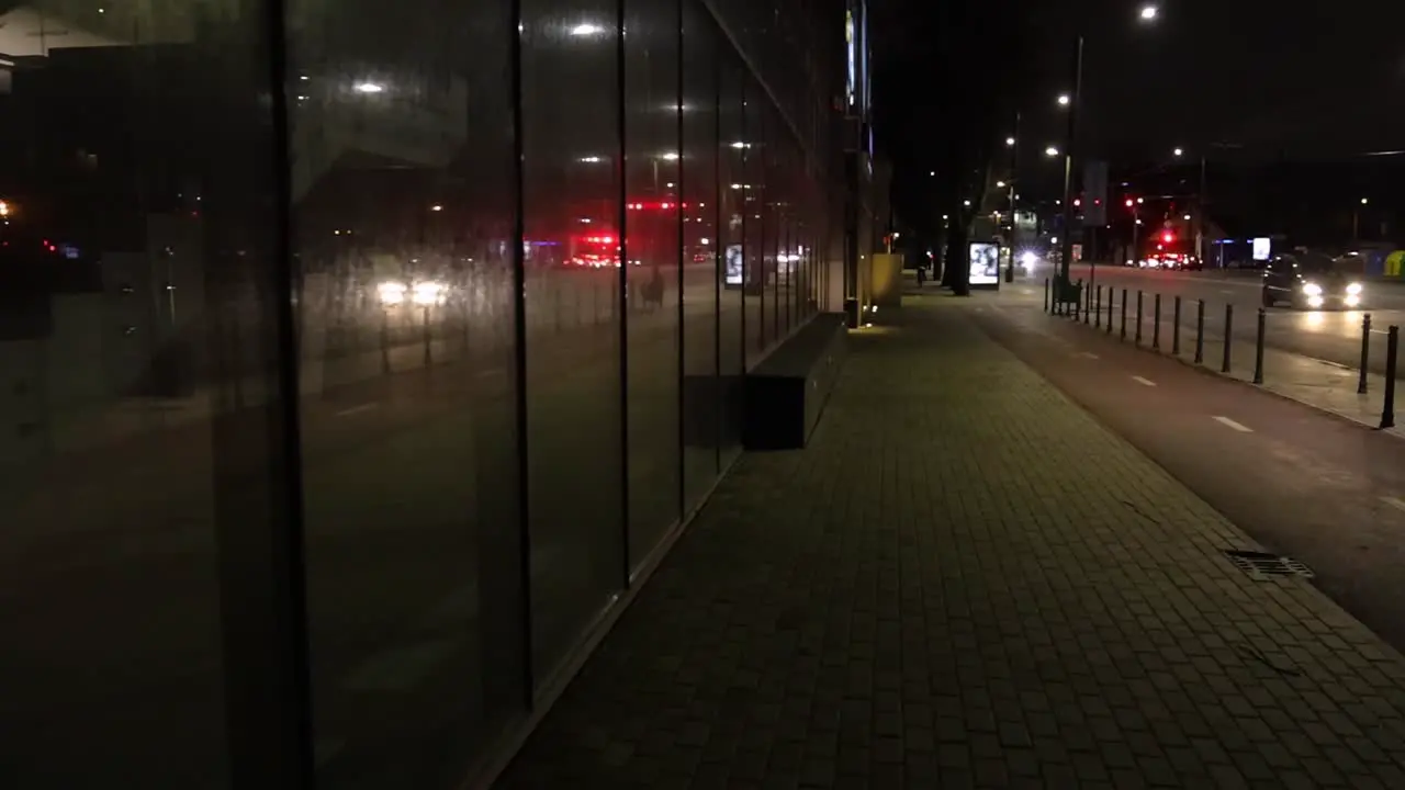 Walking in the city at night reflection in the glass wall