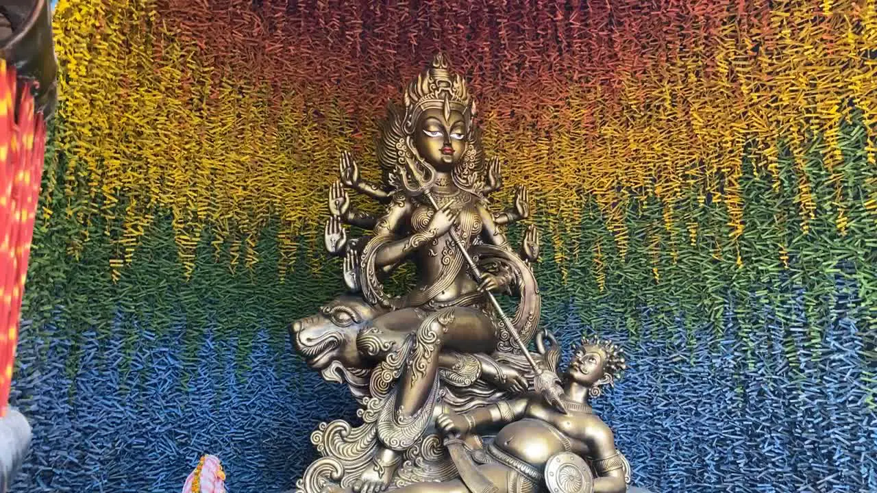 Metallic textured clay model of devi durga inside a decorated colorful pandal