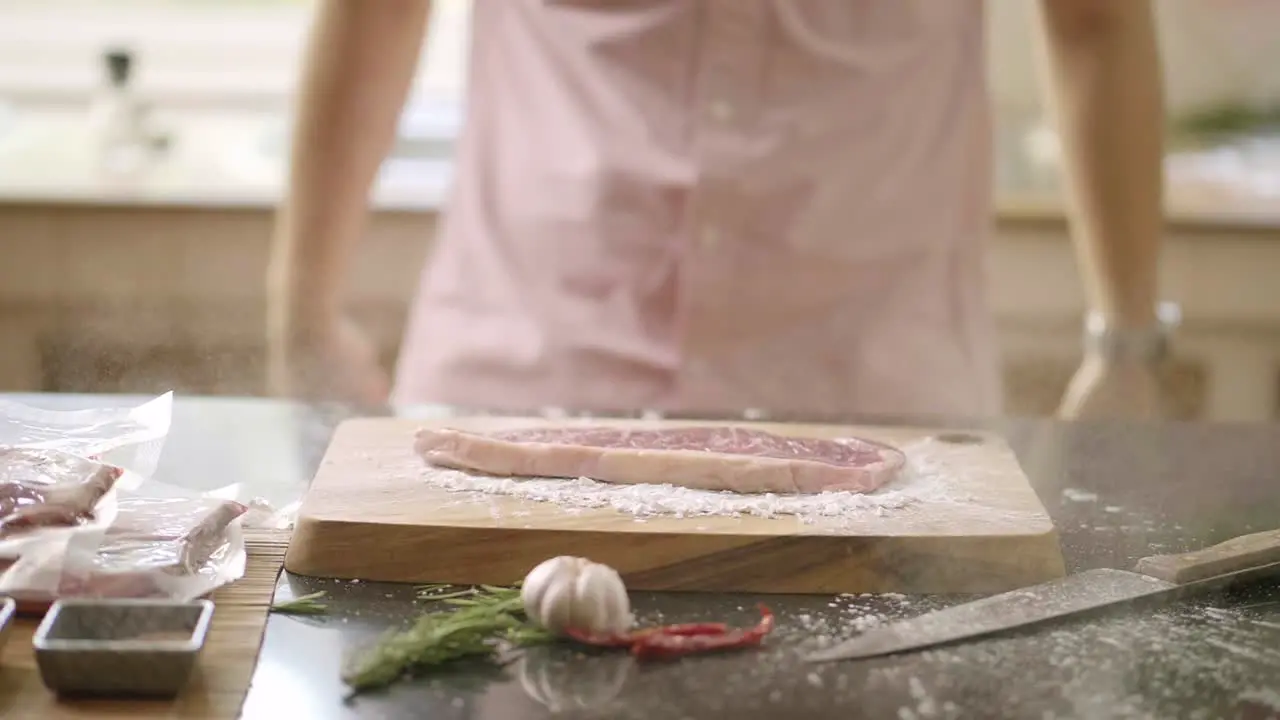 Slow Motion of Raw Steak Meat Falls On Cutting Board With Powder Explosion In Kitchen