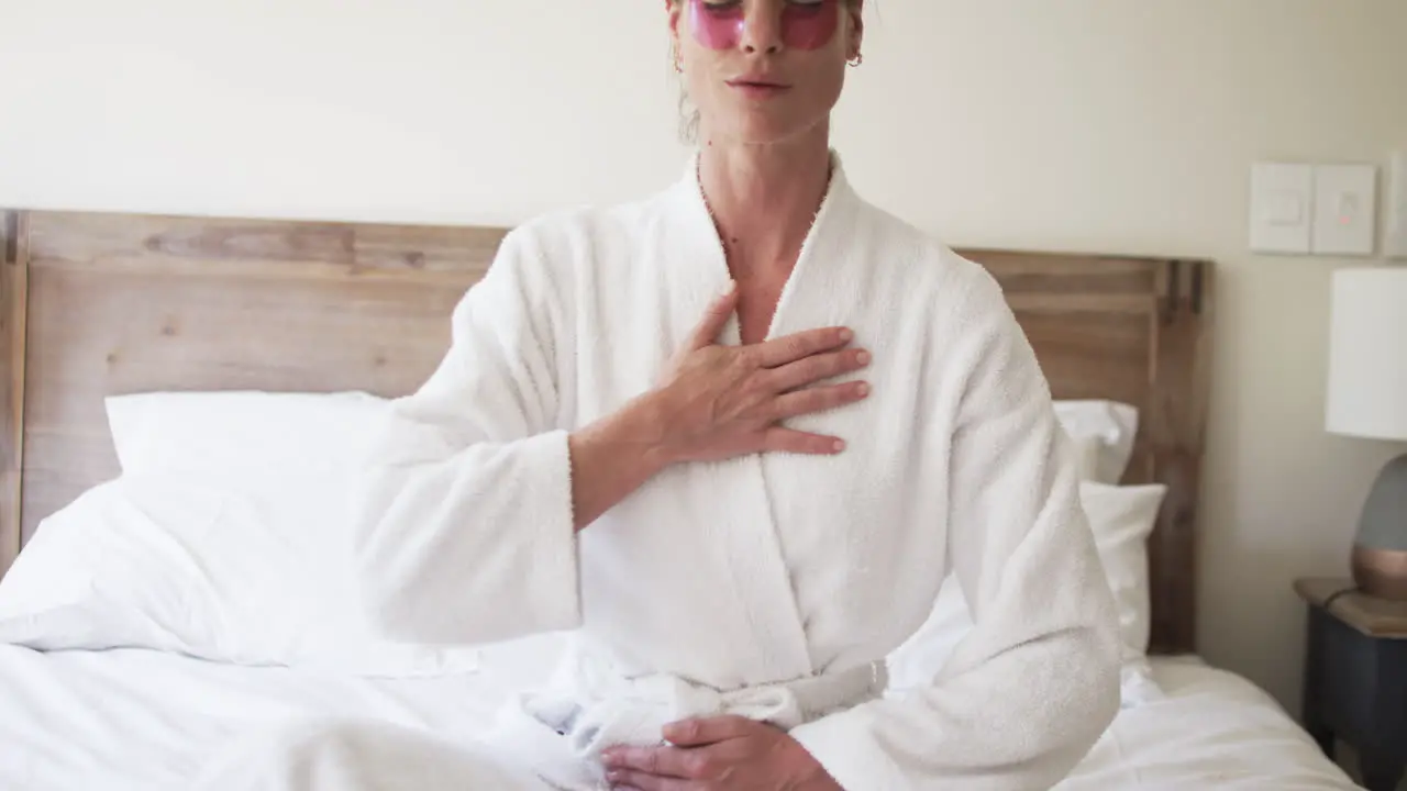 Middle-aged Caucasian woman in a bathrobe practices deep breathing at home