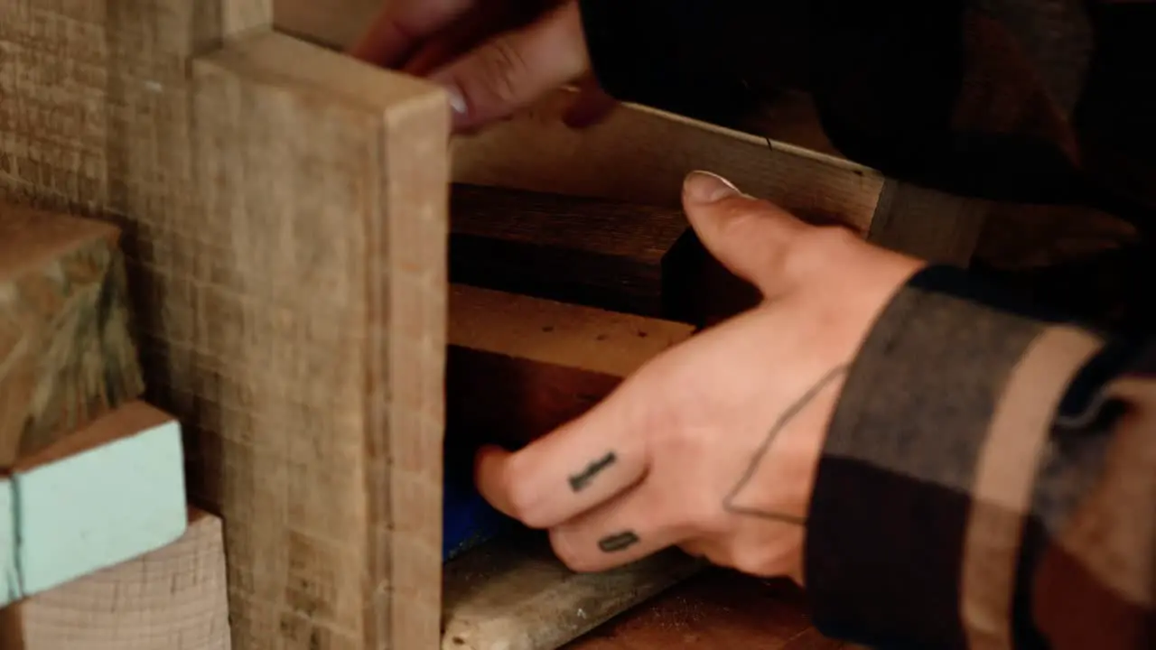 Female artist choosing a piece of wood for a project from a pile of different boards on bandsaw woodworking 4K slow-motion 60 fps