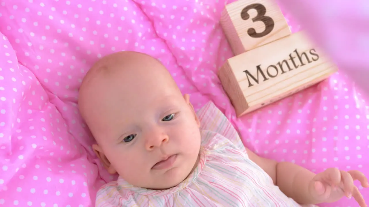 Three months baby girl in pink bassinet