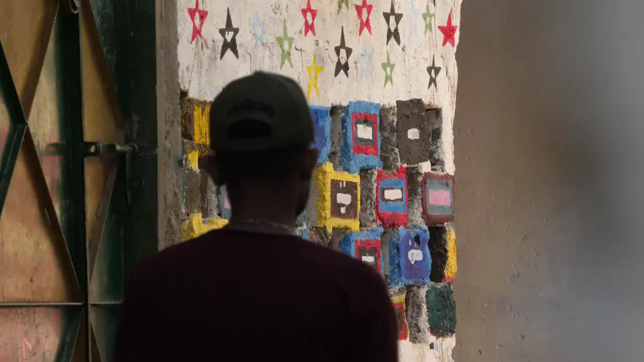 Baseball Cap Wearing Male Walking Along Wall With Coloured Tiles In Malir