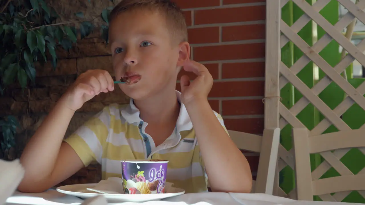 Kid eating chocolate ice cream dessert in summer cafe