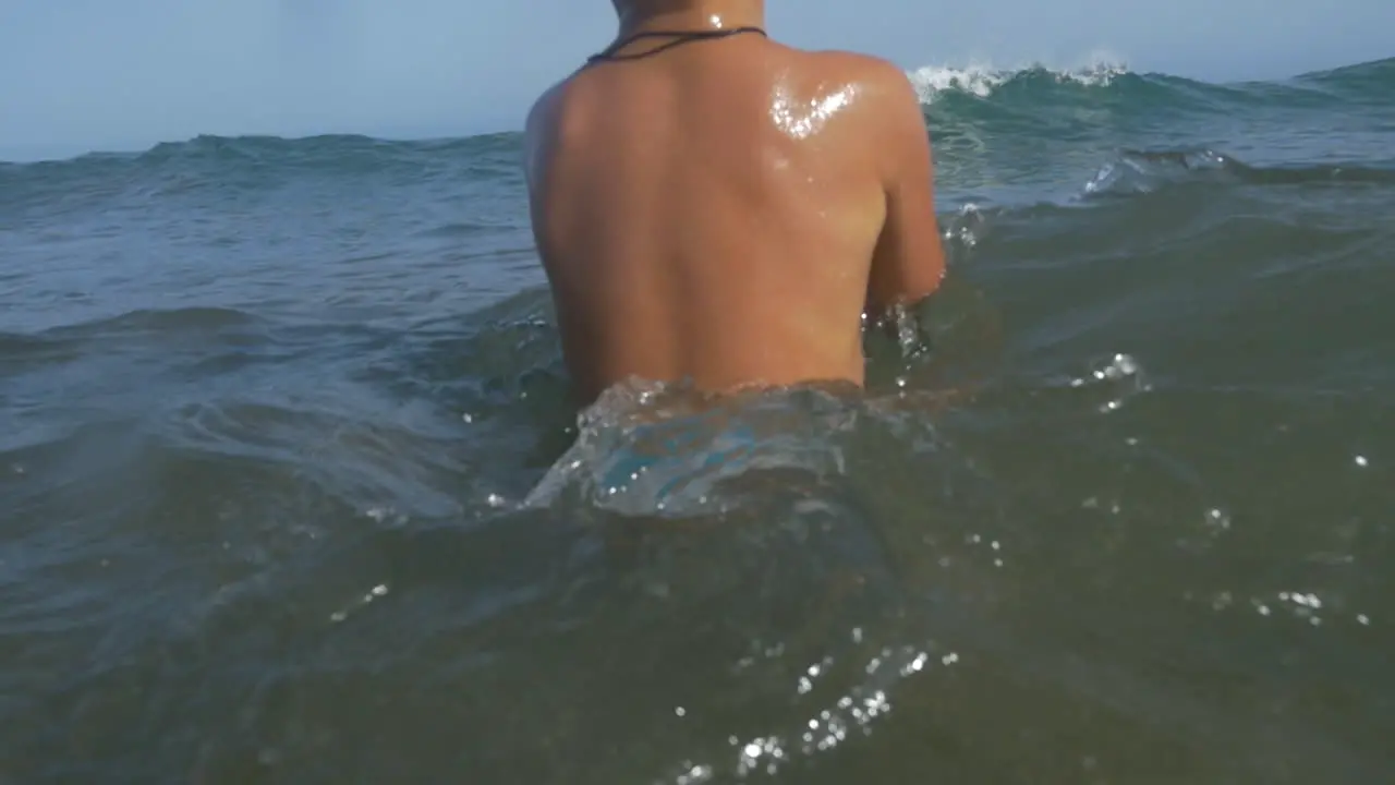 Child with ball swimming in wavy sea