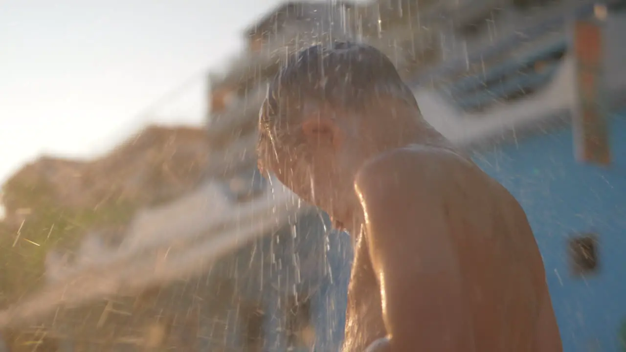 Kid is under cool beach shower outdoor