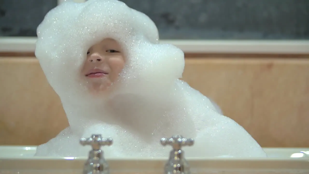 Happy child in foam taking bath