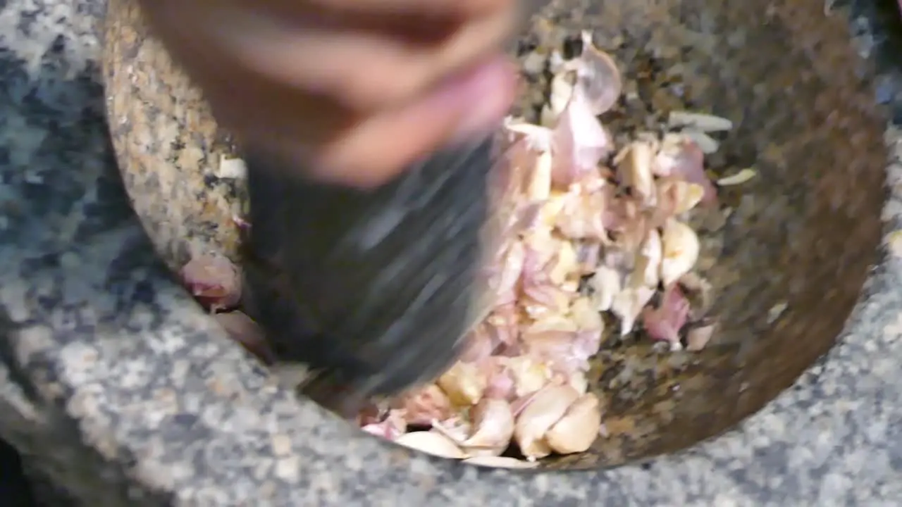 Asian Hand Using Stone Mortar and Pestle Crushing Garlic Close Up Slow-Motion