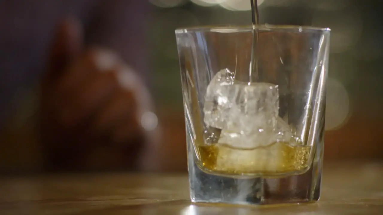 Slow Motion Shot Of Pouring Whiskey Into Glass With Ice Cubes