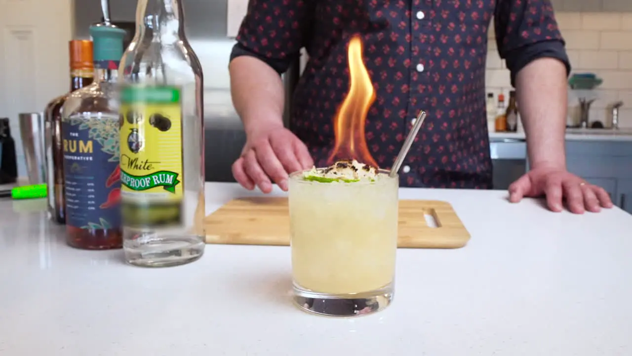 Bartender puts flaming cocktail down on bar in slow motion