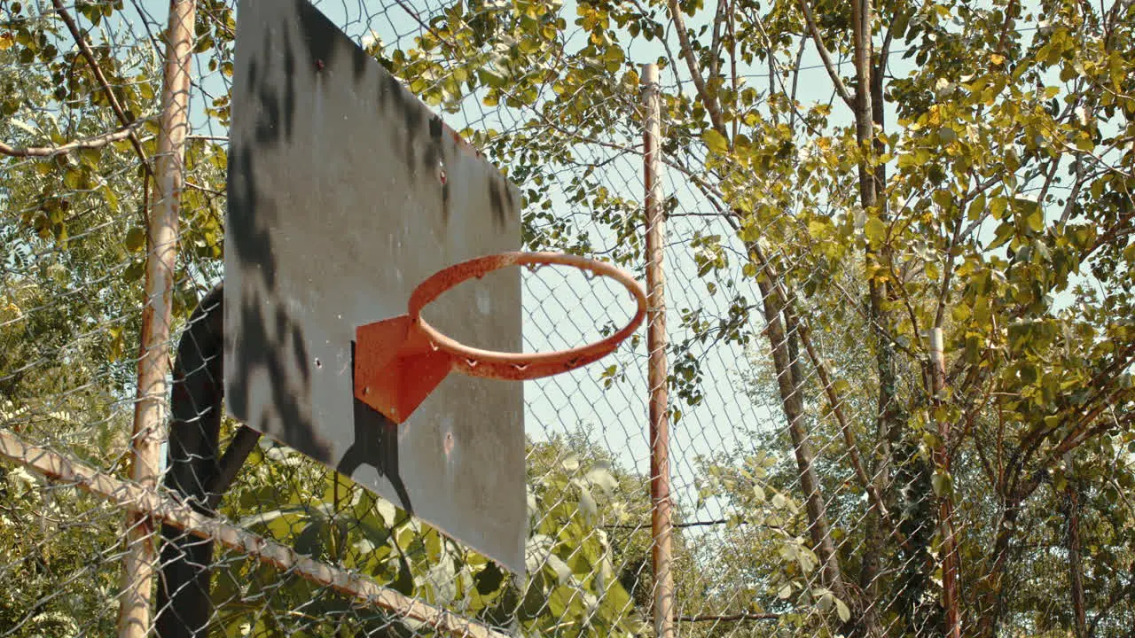 Orange Ball going through the Round Hoop Basket with Steel Backboard of Basketball in slowmo