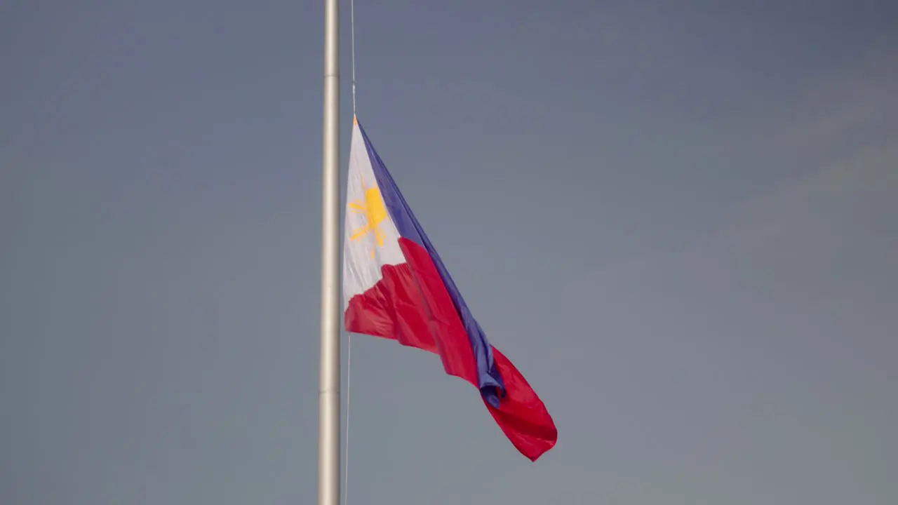 Large Philippine flag on giant flagpole with birds flying past in slow motion