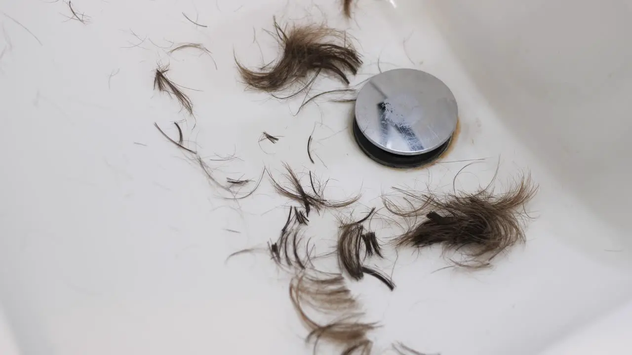 Slow motion video of hair falling into a white sink