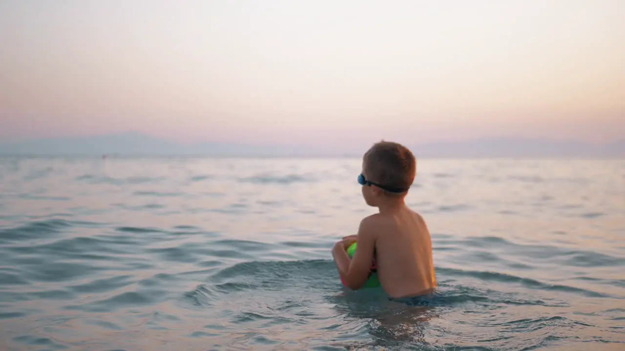 Child taking ball to water and then floating on it in the sea