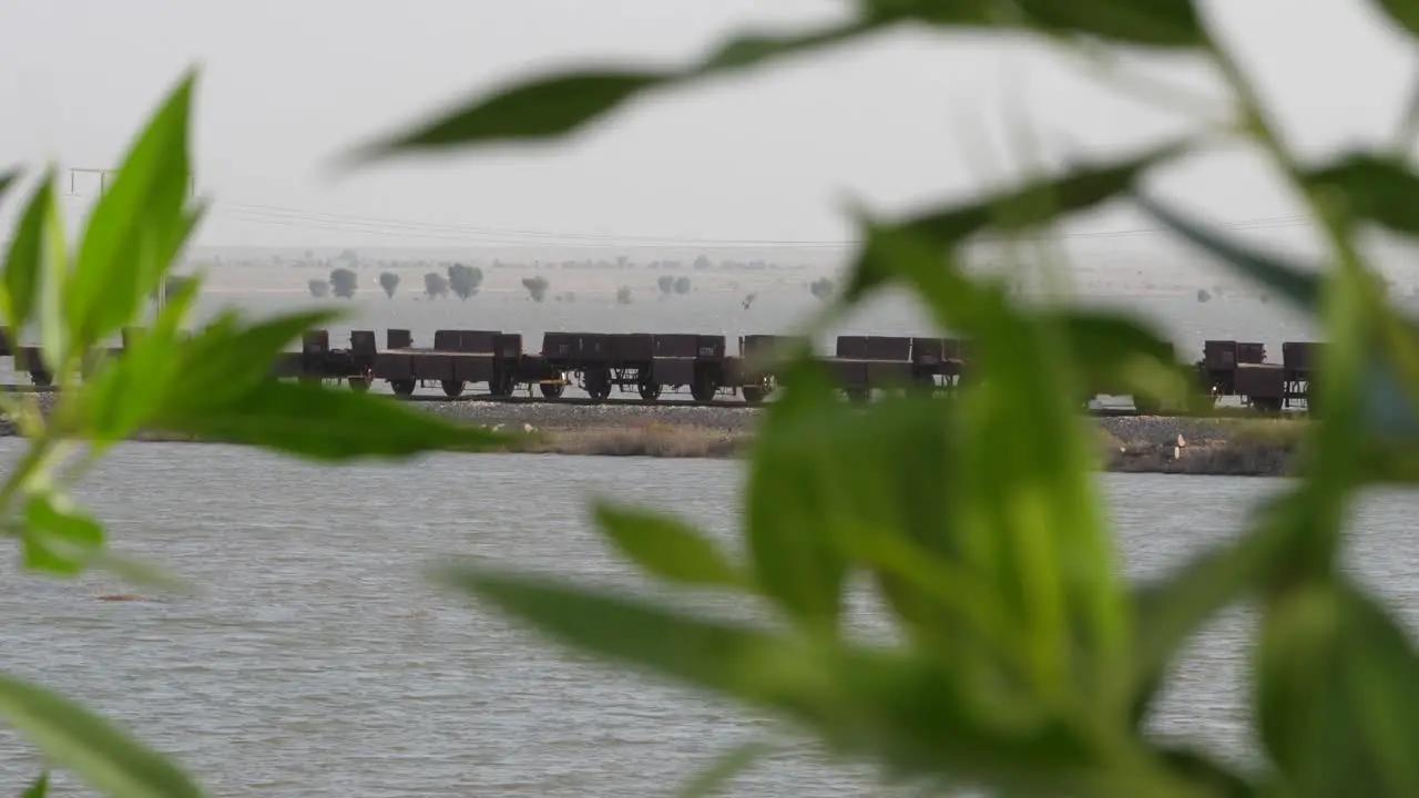 Empty Rail Wagons On Tracks Seen Through Bokeh Green Tree Branches In Sindh Pakistan