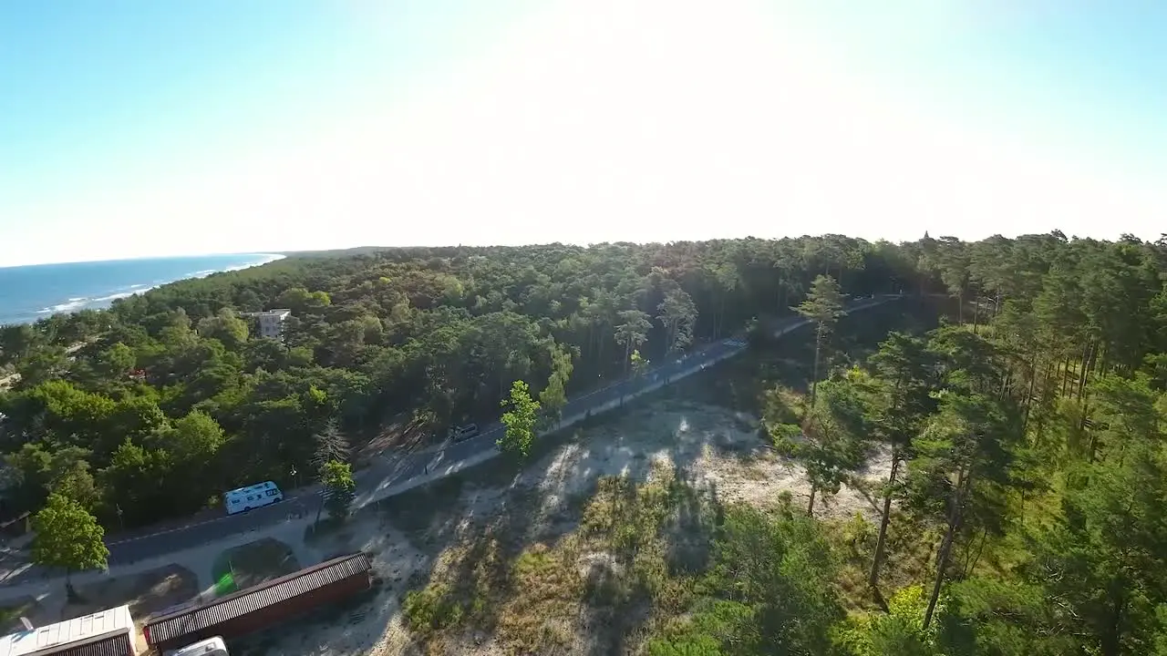 Aerial FPV Flying Towards Open Clearing Beside Forest Road Path