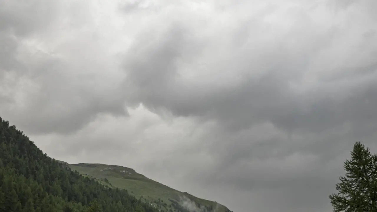 Time Lapse of fast moving clouds over an alpine forest valley with mountain peaks in the background