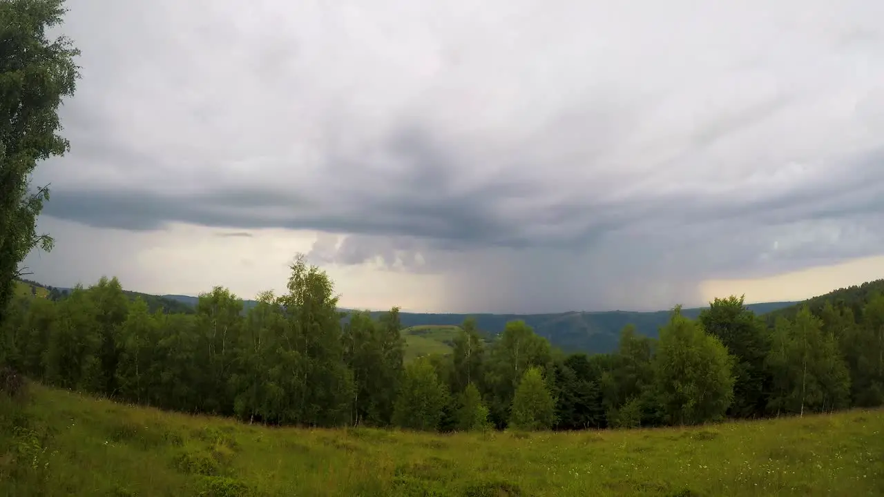 Timelapse of rain clouds approaching from the horizon over a meadow surrounded by trees