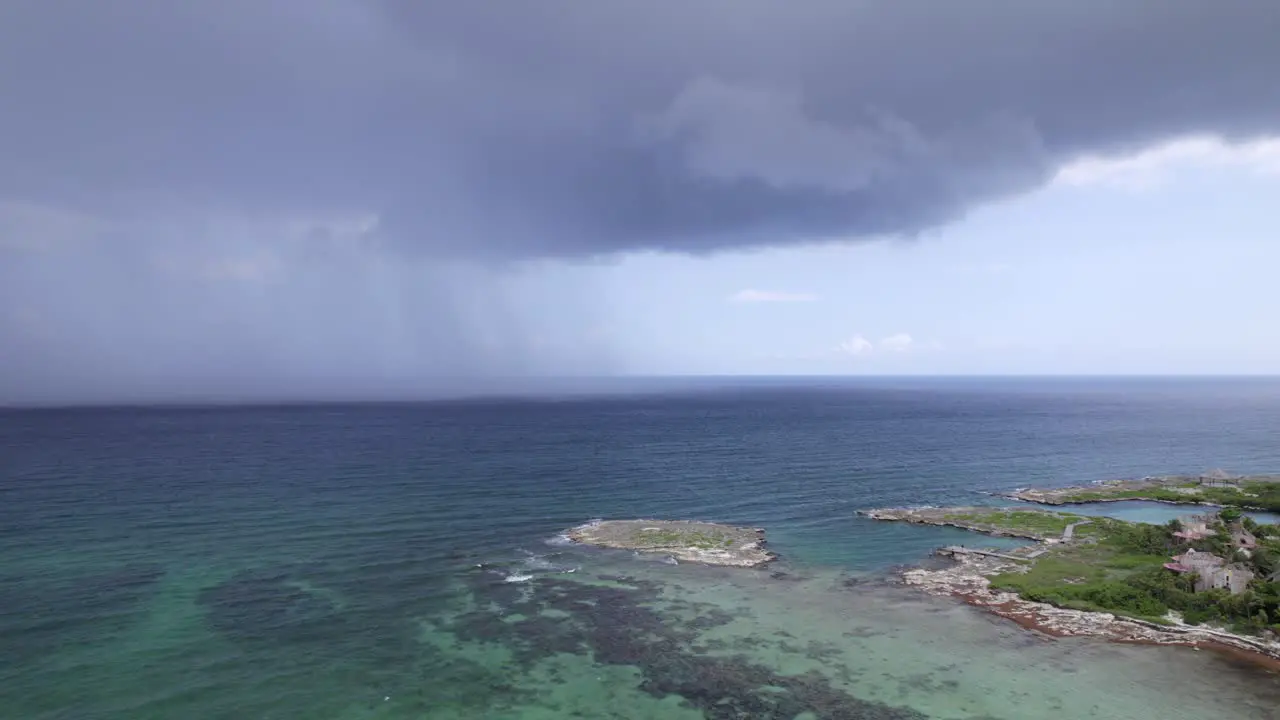 RAIN IN THE CARIBBEAN SEA NEXT TO AN ABANDONED HOTEL DRONE SHOOT TRACKING SIDEWAYS