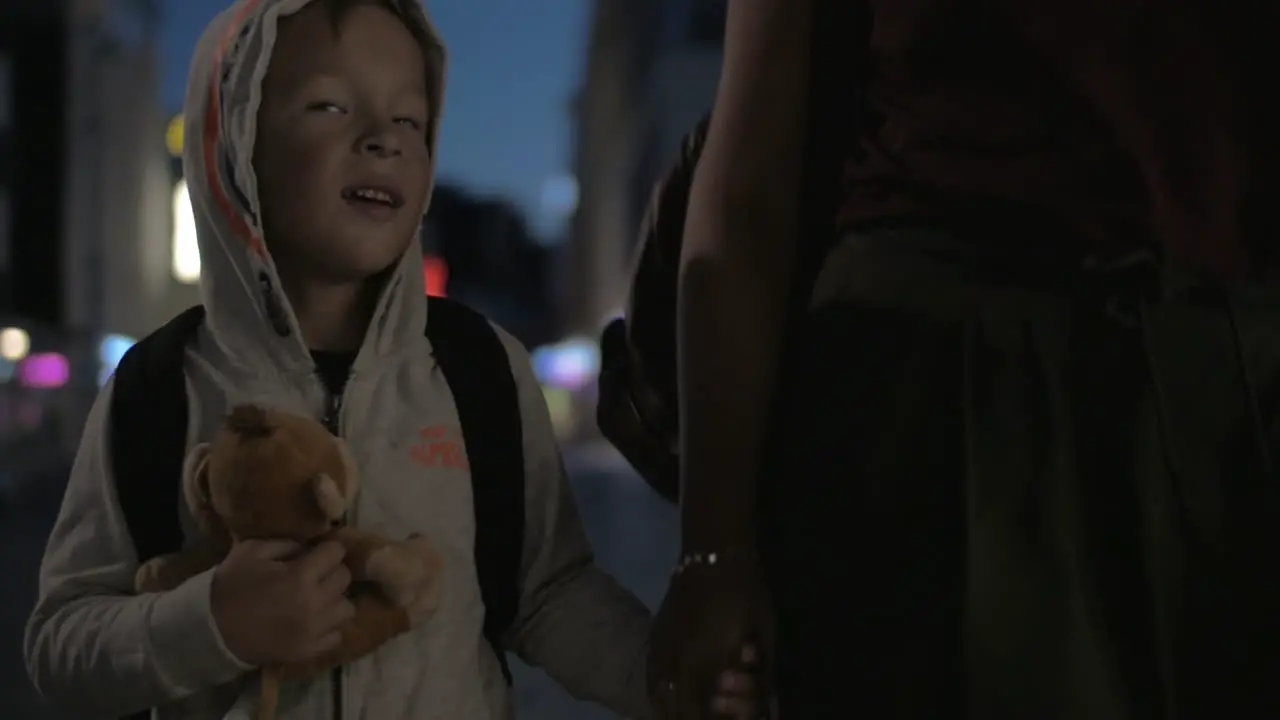 Child walking in night city with mom