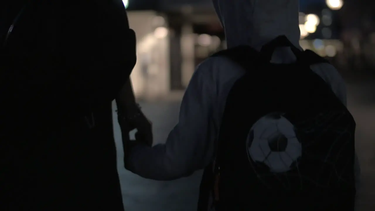 Child and mother holding hands while walking at night