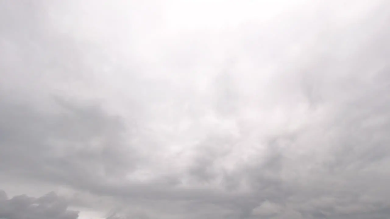 Static shot of grey clouds slowly moving through the bright sky