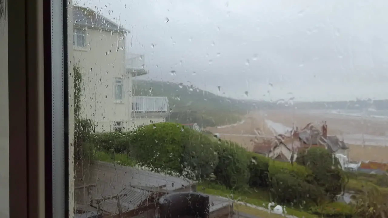 Rain Drops Hitting a Glass Window with a Beach View in Slow Motion