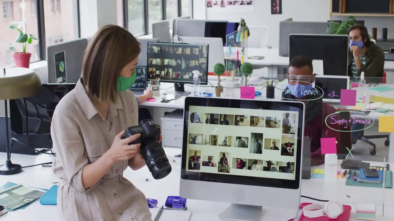 Caucasian businesswoman wearing face mask using a camera in modern office