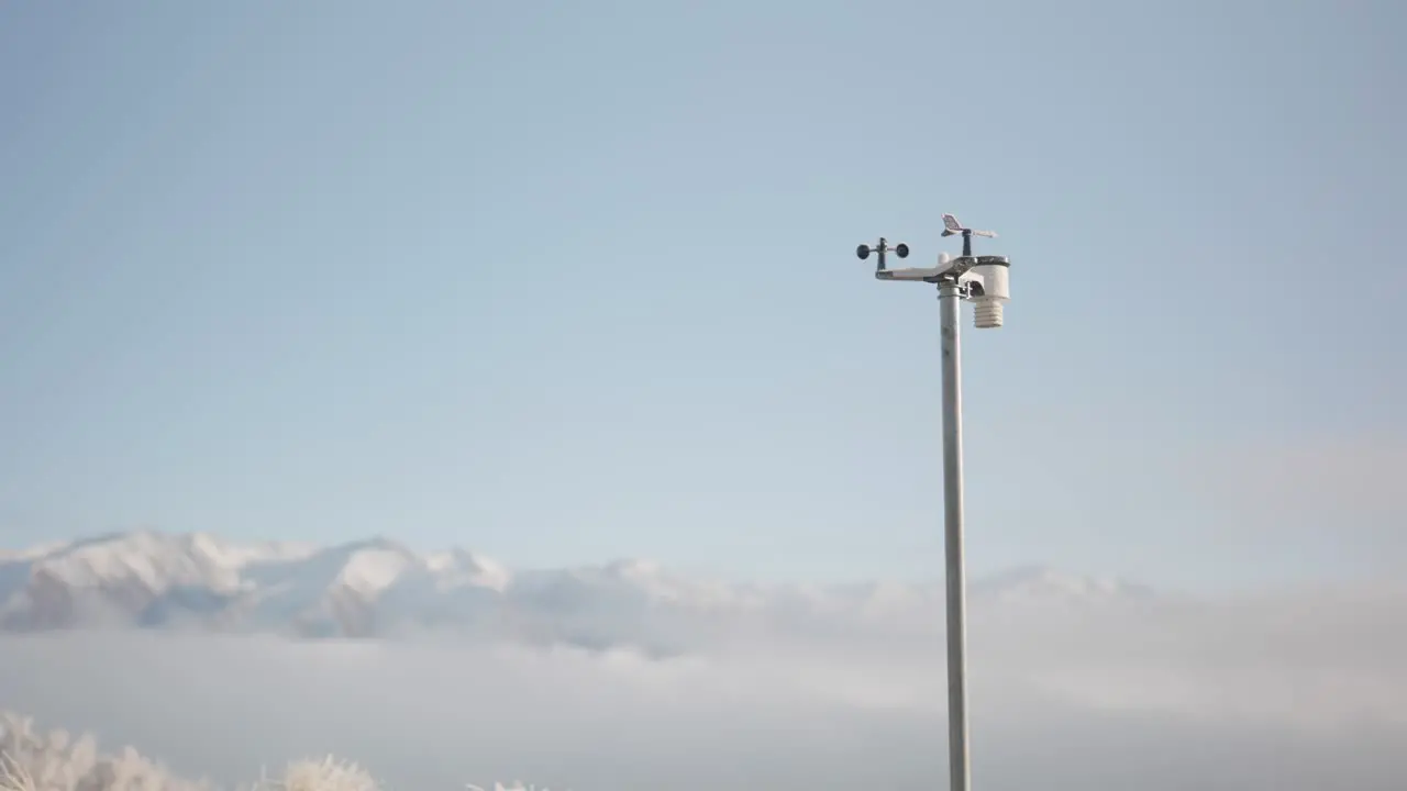 Pole mounted weather station in front of majestic snowy mountains