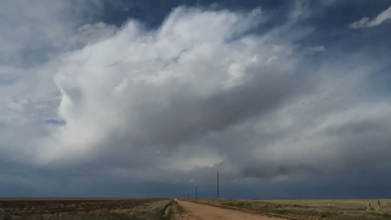 Dark clouds move rapidly over a dirt road on the plains