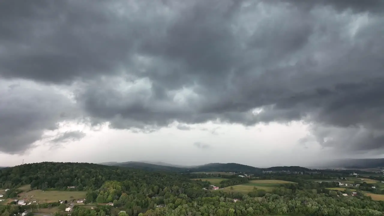 A descending aerial view of a big rainstorm moving over the countryside