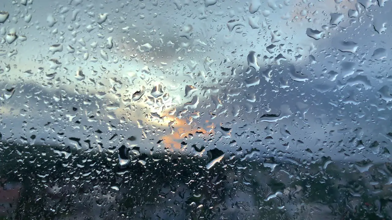 Close up of raindrops at window blurred sunset in background